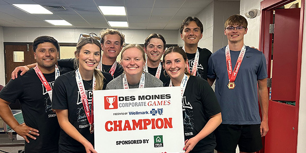 A group of young adults smiling with a sign that says" Champion" 